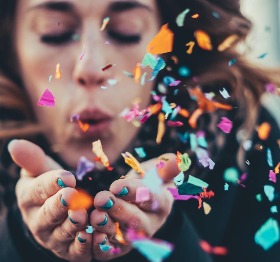 woman blowing paper strips in selective focus photography